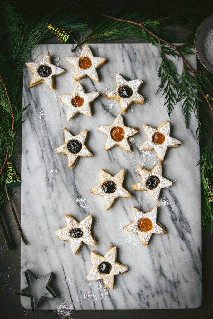 overhead view of 12 vegan linzer cookies on a marble board never to evergreens