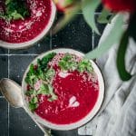 overhead shot of a bowl of vegan beet carrot ginger soup with cilantro and sesame