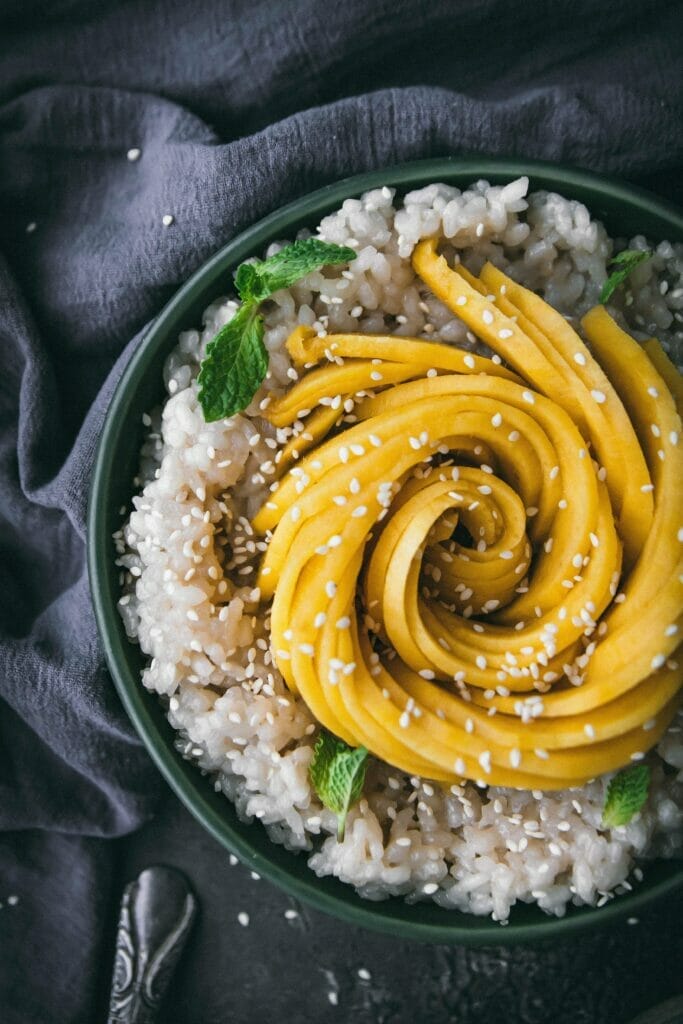close up overhead view of vegan mango sticky rice in a green bowl