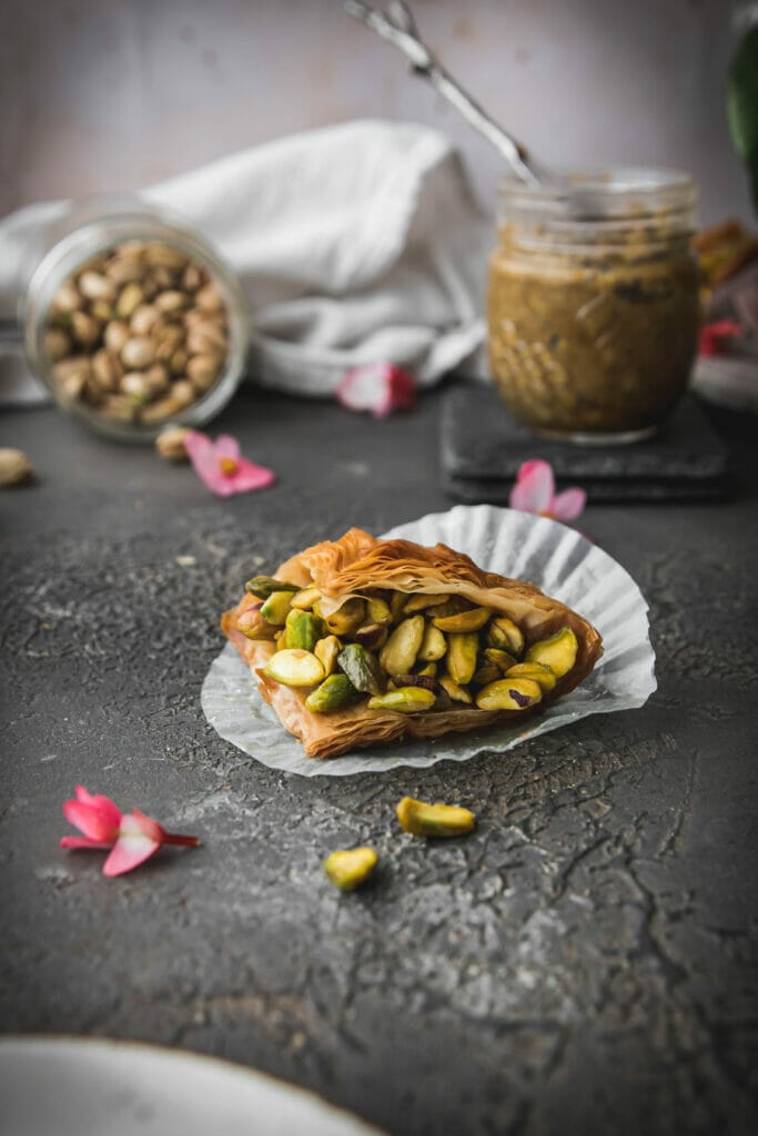 side view of a triangle of baklava with whole pistachios