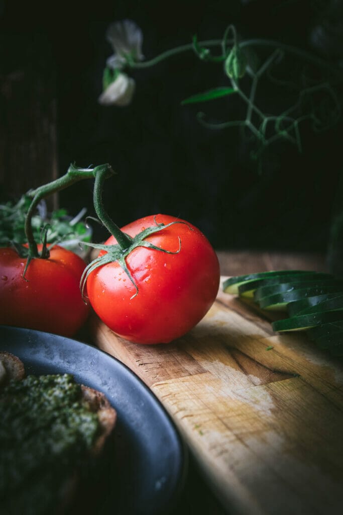 side view of a red tomato on a vine on a table