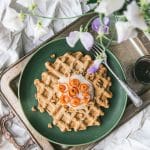 vegan carrot cake waffle on a breakfast tray next to a vase of flowers