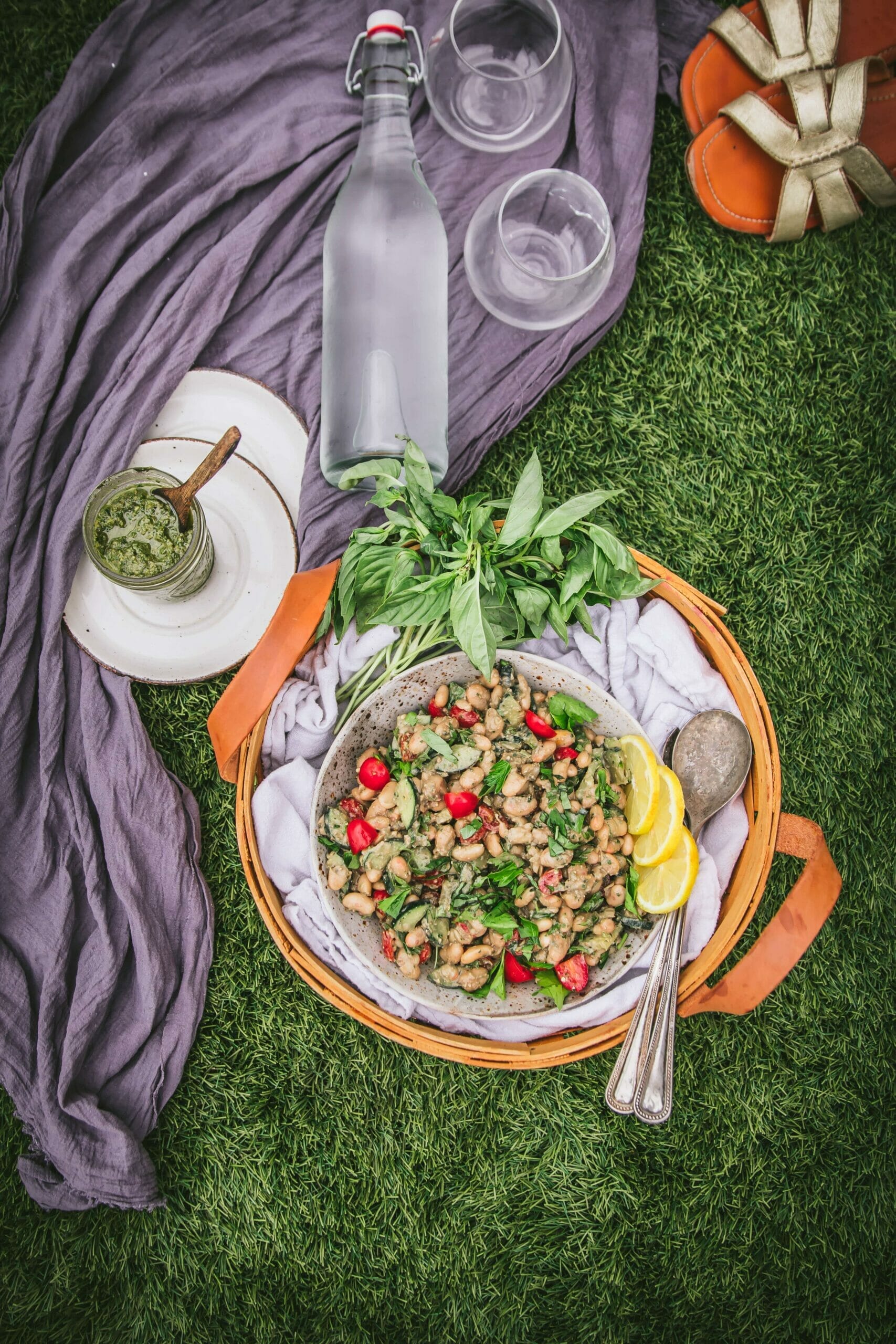 overhead shot of a bowl of pesto white bean salad on the grass