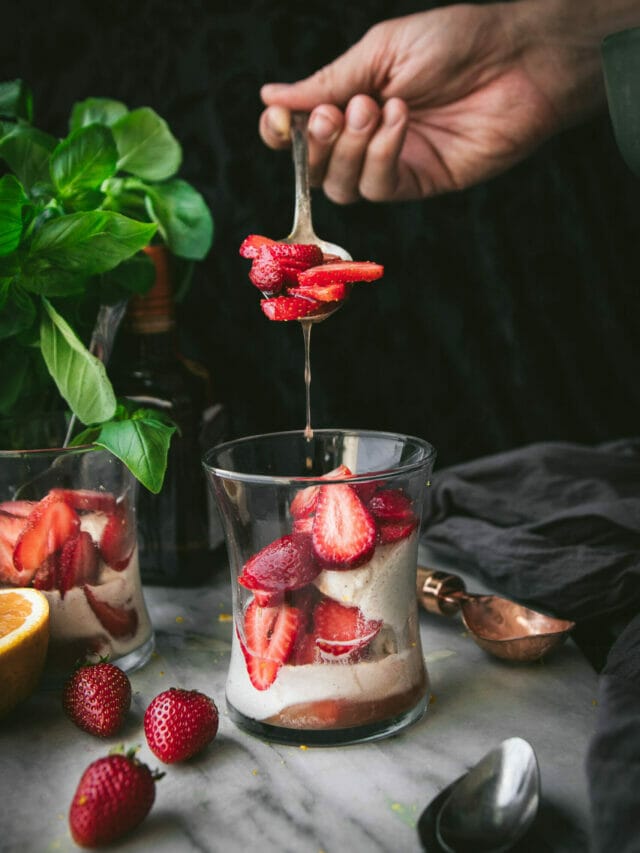 hand spooning strawberries into a grand marnier sundae