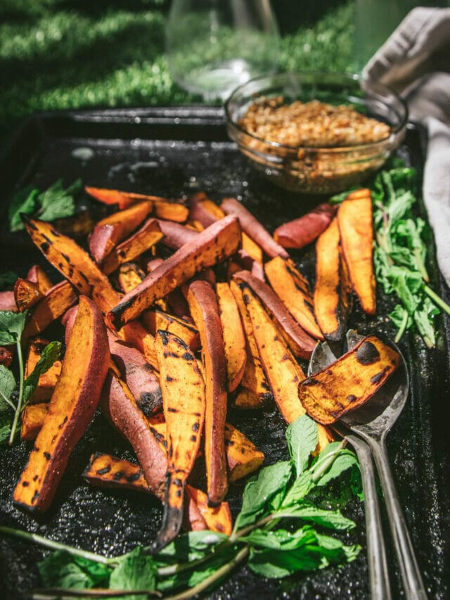 side view of grilled sweet potato wedges on a sheet tray