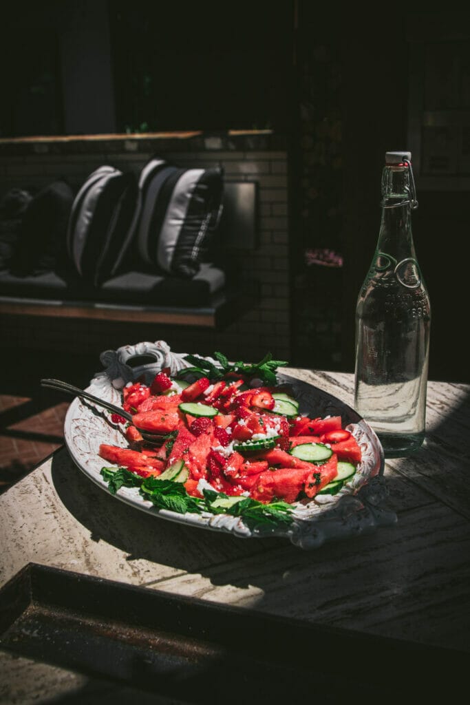 a side view of a plate of watermelon cucumber and feta salad on an outdoor table