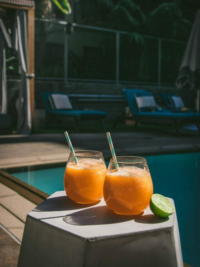 two melon agua frescas on a table next to a pool