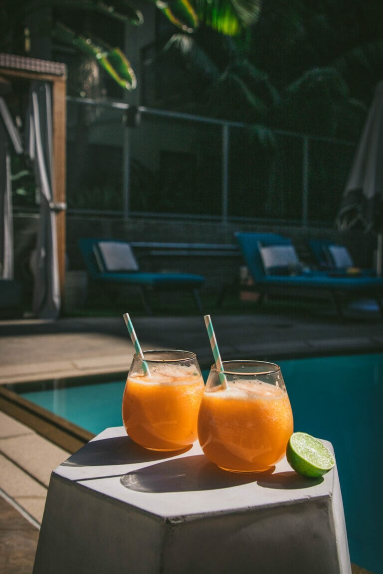 two melon agua frescas on a table next to a pool