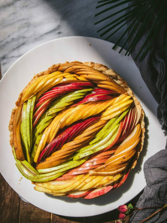 overhead view of a woven fresh pear tart with multiple colors