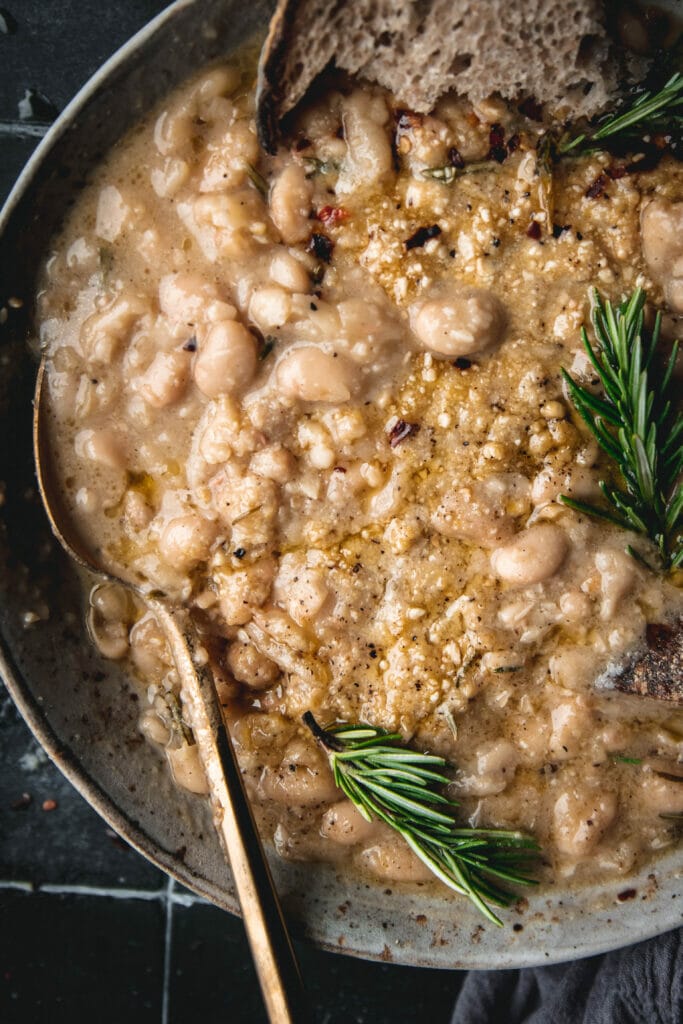 close up of vegan olive oil braised white beans with rosemary