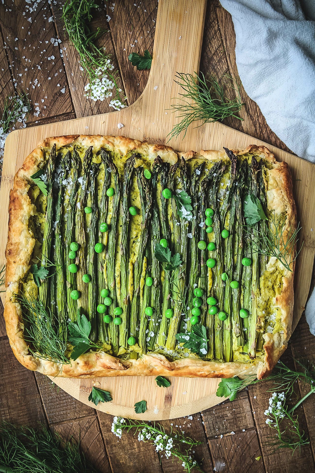 overhead shot of a vegan asparagus ricotta galette on a wooden board