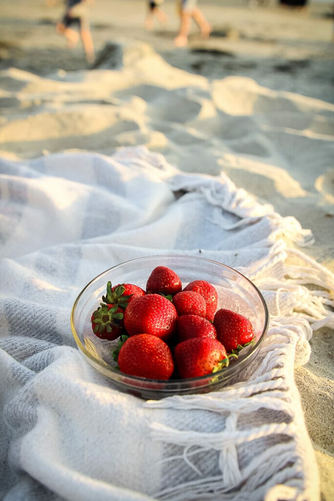 bowl of strawberries on a beach blanket