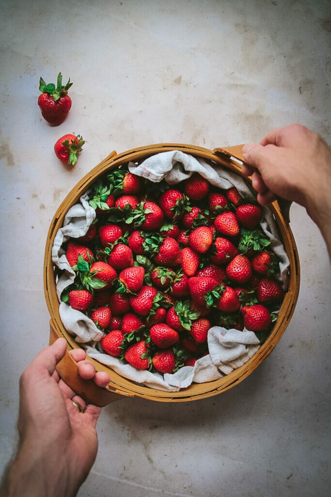 hands holding a basket of strawberries