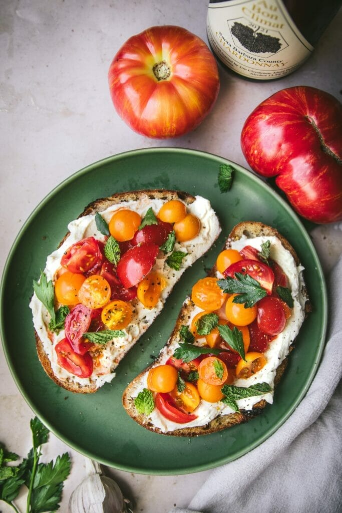 two pieces of whipped ricotta tomato toast on a plate