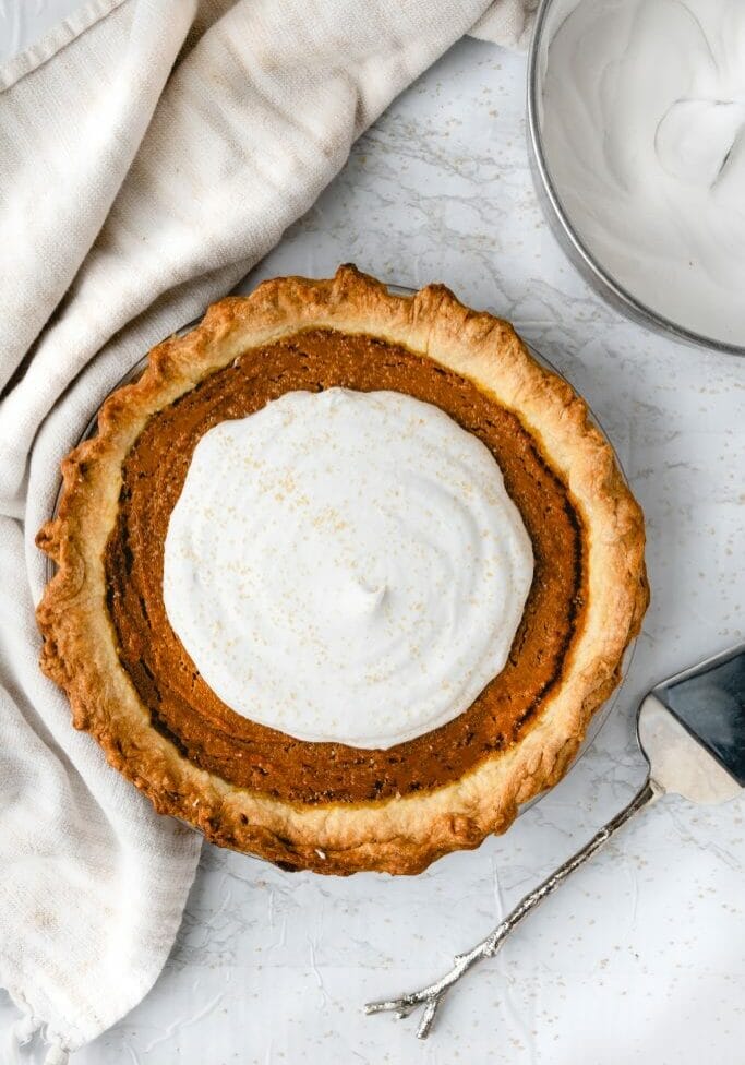 overhead shot of vegan pumpkin pie with coconut whipped cream and a silver spoon