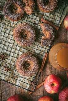 glass of apple cider next to baked apple cider donuts