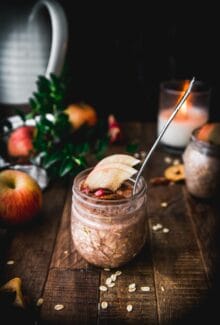 side view of apple pie overnight oats on a wooden table next to an apple