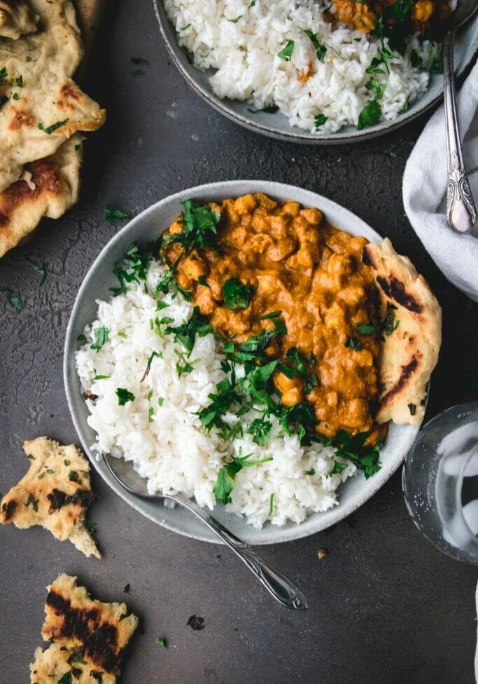 bowl of butter chickpeas next to ripped naan