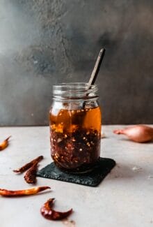 jar of homemade chili crisp with a wooden spoon sticking out