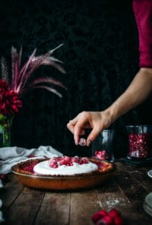 hand placing sugared cranberry on top of vegan custard pie