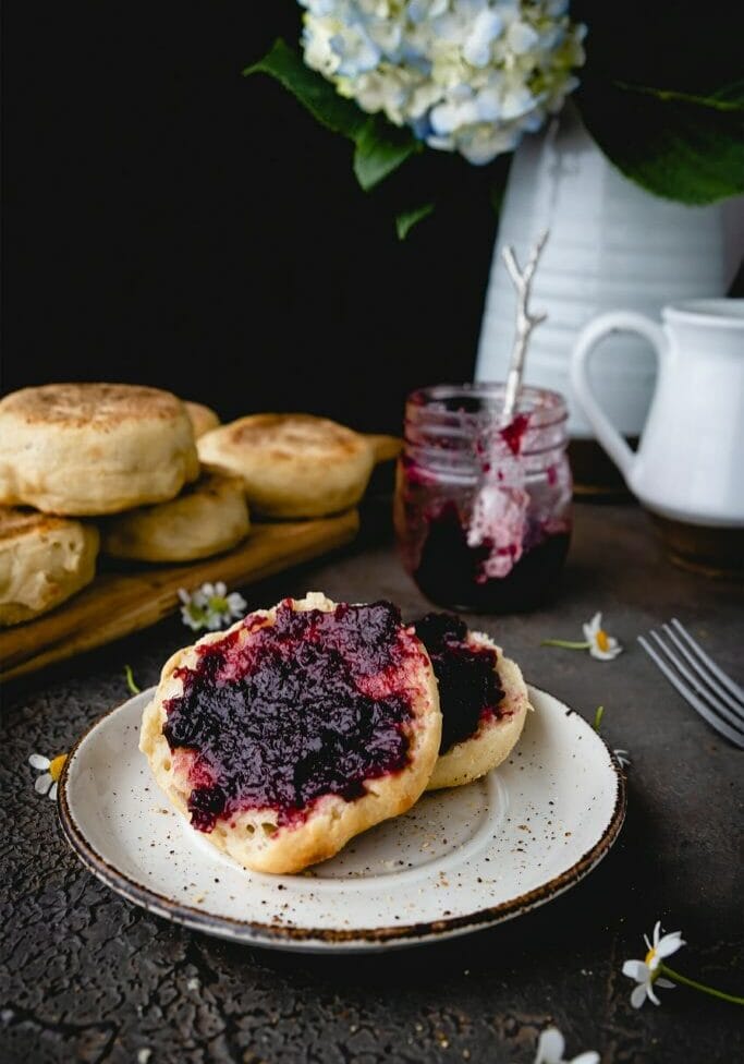 sliced open english muffin spread with blackberry jam