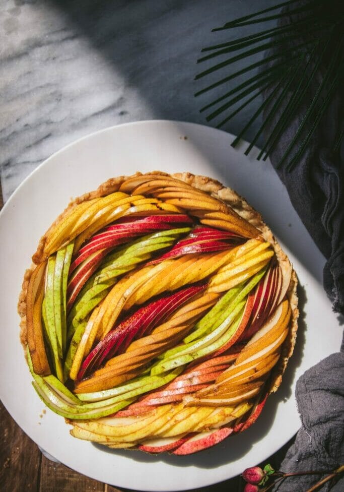 overhead view of a woven fresh pear tart with multiple colors