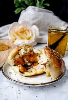 broken open garlic rolls on a white plate next to garlic olive oil in a jar