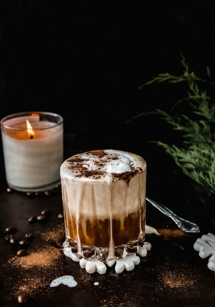 side view of vegan white Russian cocktail with gingerbread spices on dark tray