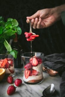 hand spooning strawberries into a grand marnier sundae
