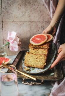 hands placing a grapefruit poppyseed load cake on a tray