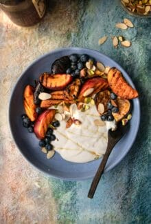overhead shot of grilled peach yogurt bowls on next to chopped nuts