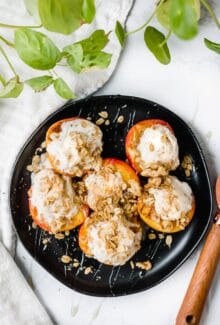 black circular plate with six grilled peaches with ice cream