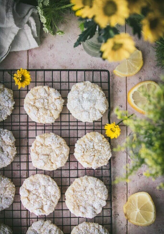overhead shot of vegan lemon crinkle cookies on a stone table next to yellow flowers