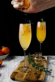hand squeezing orange juice into a mimosa flute glass