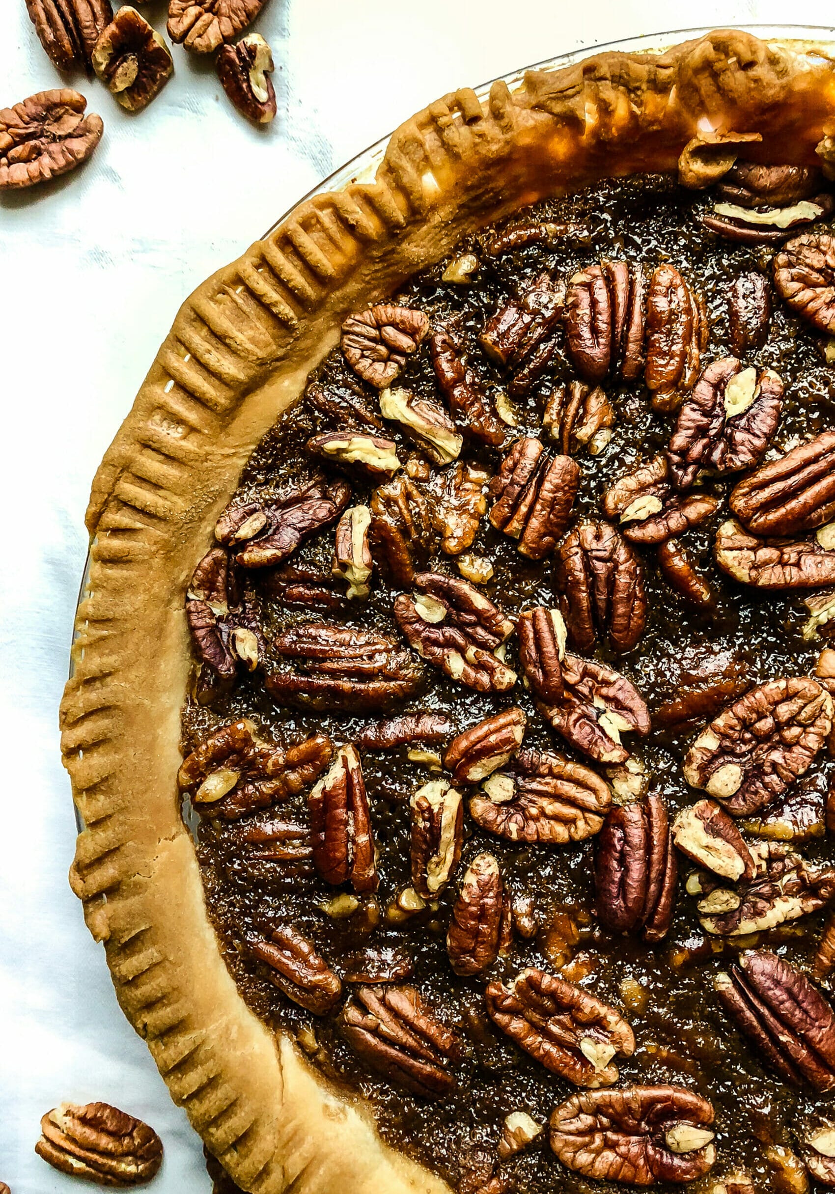 side birds eye view of vegan pecan pie in a pie plate on a white table
