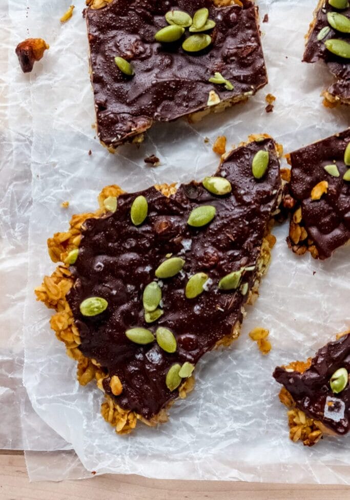 close up overhead shot of oat granola bar with a dark chocolate coating and pumpkin seeds on top