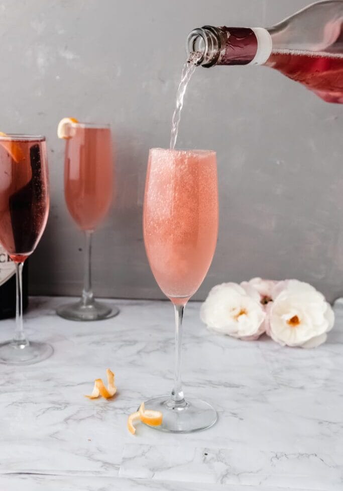 sparkling rose pouring into a champagne flute of rose french 75