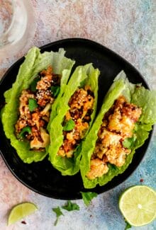 three lettuce wraps filled with sticky sesame cauliflower on a black plate