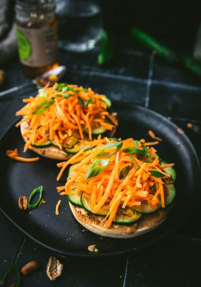 two pieces of Thai peanut bagel slices with carrots and cucumbers