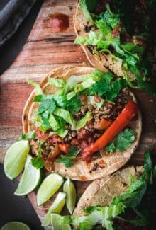close up of walnut lentil taco meat in a tortilla with peppers and limes